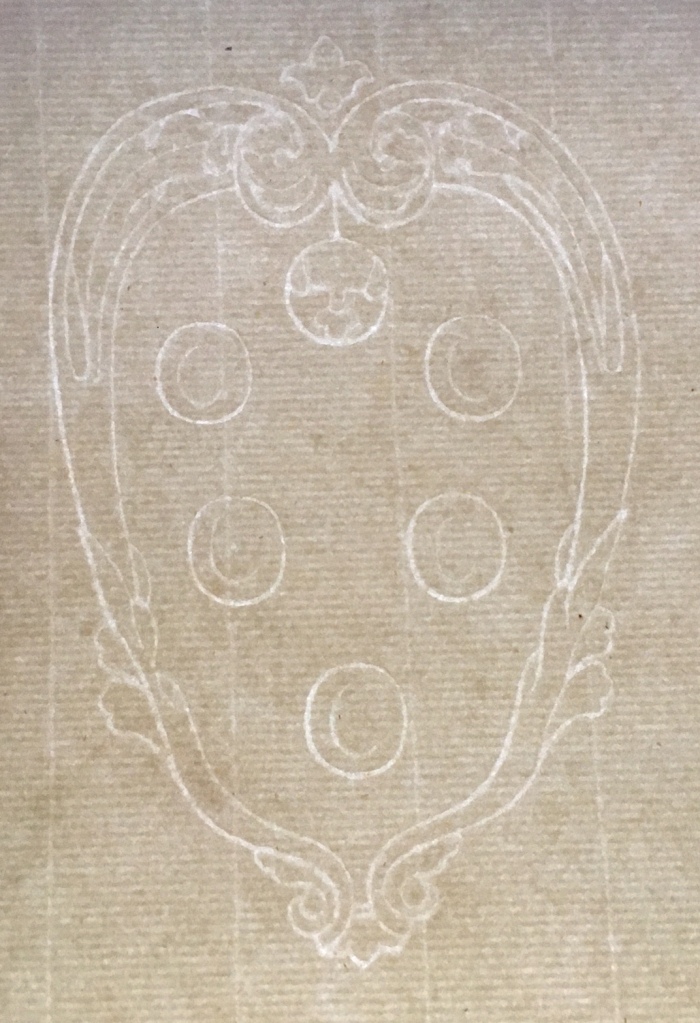 A watermark on off white paper, it is an ornate scrolled elongated oval with five interior rounds with feint marks, the top one possibly a bird in flight