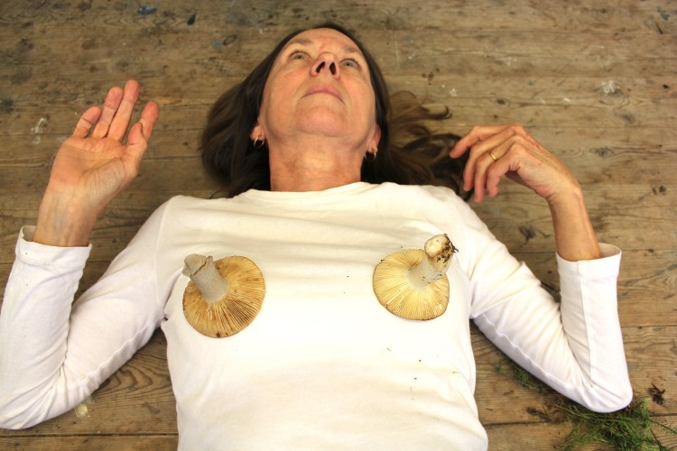 Balancing two mushrooms on chest - a surreal image that intends to imply interconnectedness of body and world
