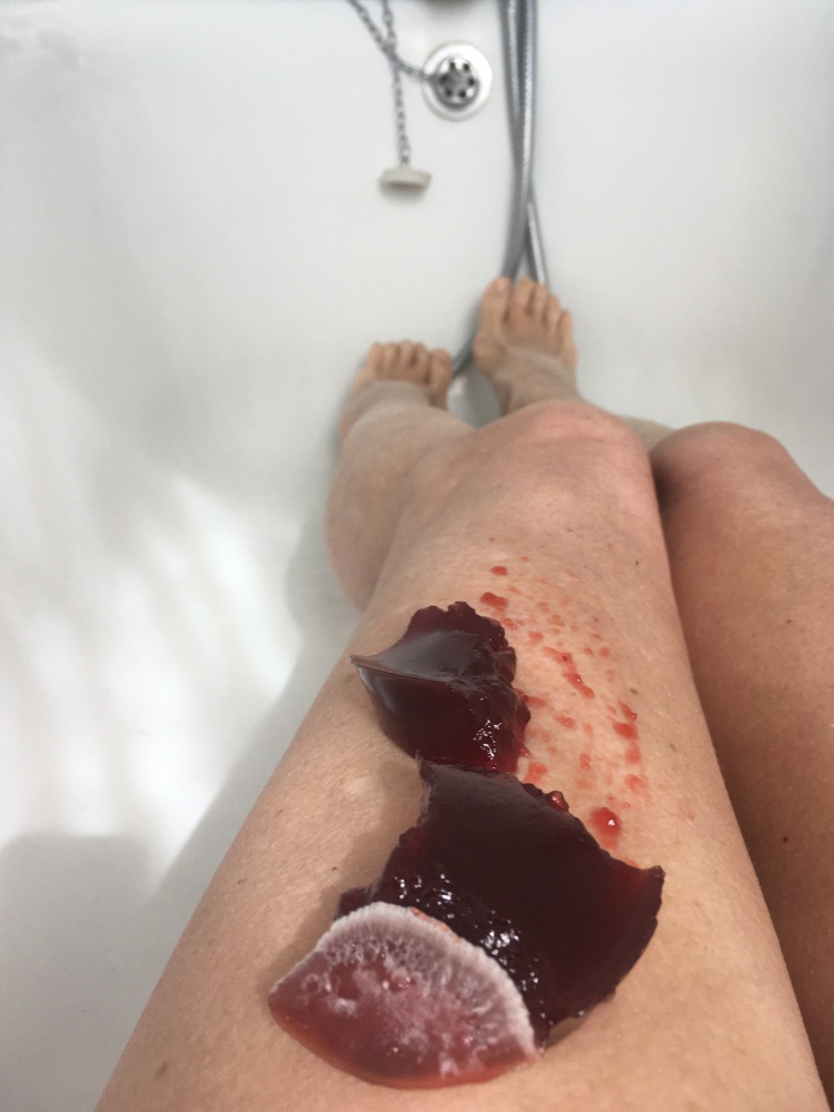 Naked legs in a bath tub - a surreal image that intends to imply interconnectedness of body and world